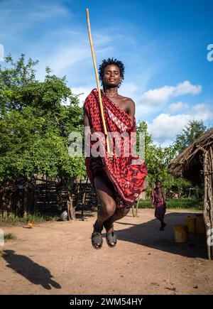 Un giovane guerriero Maasai esegue la danza tradizionale del salto nel suo villaggio di Mikumi, Tanzania Foto Stock