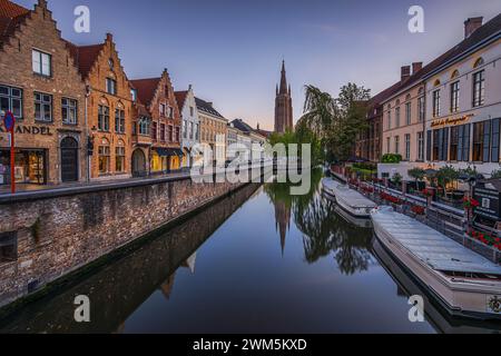 Vista su un canale nella città vecchia di Bruges. Atmosfera serale con le storiche case delle corporazioni e le case dei mercanti. Riflessi sulla superficie dell'acqua. Foto Stock