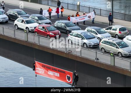 Kehl, Germania. 24 febbraio 2024. Due attivisti per il clima scendono dal ponte di Europabrücke tra Kehl in Germania e Strasburgo in Francia con uno striscione che recita "Stop mortale Global Warming - Together”. Circa 20 attivisti di Last Generation e del suo movimento sorella francese Riposte Alimentaire hanno preso parte all'azione sul Ponte Europa. Crediti: Jason Tschepljakow/dpa/Alamy Live News Foto Stock