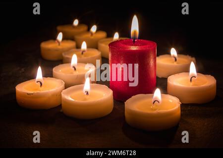 Molte candele bianche e una in fiamme, messa a fuoco selettiva Foto Stock