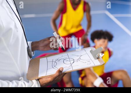 Il coach delinea la strategia sugli appunti del campo di pallacanestro al coperto Foto Stock