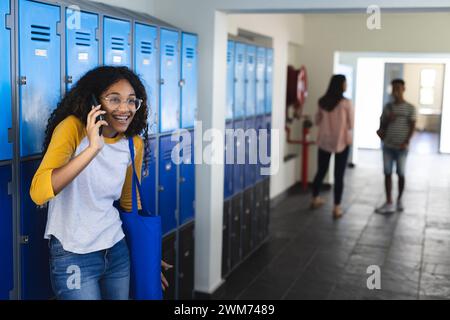 Un ragazzo birazziale adolescente cammina in un corridoio della scuola superiore con spazio per le copie Foto Stock