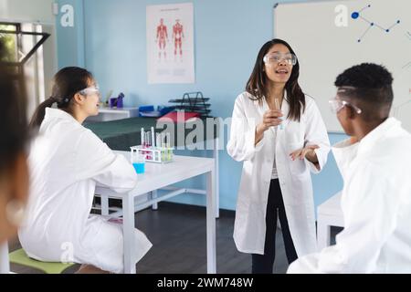 Un giovane insegnante birazziale insegna in un laboratorio di scuola superiore Foto Stock
