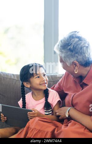 Una ragazza birazziale ama leggere con la nonna a casa Foto Stock