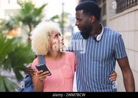 Una coppia birazziale varia gode di una passeggiata all'aperto in città Foto Stock