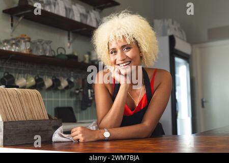 La giovane donna birazziale sorride calorosamente in un ambiente di cucina di casa Foto Stock