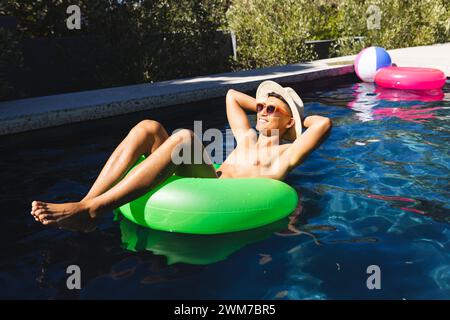 Il giovane asiatico si rilassa su un galleggiante in una piscina Foto Stock