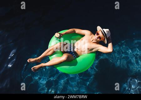 Il giovane uomo asiatico si rilassa su un galleggiante della piscina Foto Stock