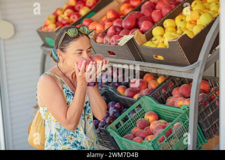 Donna matura che sceglie frutta in un negozio di strada Foto Stock