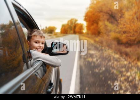 Ragazzo che mette la testa e le mani fuori dalla macchina Foto Stock