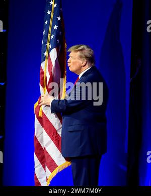 National Harbor, Stati Uniti. 24 febbraio 2024. L'ex presidente Donald Trump abbraccia e bacia la bandiera degli Stati Uniti mentre arriva alla Conferenza sull'azione politica conservatrice (CPAC), sabato 24 febbraio 2024, al National Harbor, Maryland. Migliaia di attivisti conservatori, funzionari eletti e esperti si sono riuniti per ascoltare gli oratori con il tema di quest'anno "CPAC: Where Globalism Goes to Die". Foto di Mike Theiler/UPI credito: UPI/Alamy Live News Foto Stock