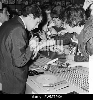 20 maggio 1964. Rotterdam, Paesi Bassi. - Il cantante belga di origine italiana, Adamo, Salvatore Adamo, tra i suoi fan, in una sessione di autografi. Firmare il braccio della donna Foto Stock