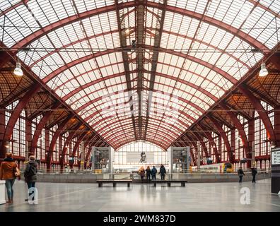 Sala dei treni della stazione centrale di Anversa. Vista simmetrica del grande capannone arioso con travi in metallo color Bordeaux. Foto Stock