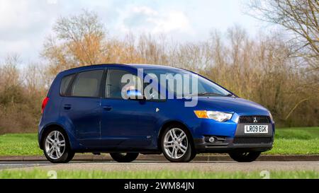 Milton Keynes, Regno Unito - 23 febbraio 2024: 2009 auto Mitsubishi Colt blu che guida su una strada inglese Foto Stock