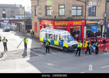 Bradford, Regno Unito. 24 FEBBRAIO 2024. La polizia protegge il decollo di Salah sulla Leeds Road in previsione dell'arrivo della marcia del West Yorkshire per la Palestina, il negozio può ancora essere visto danneggiato a seguito di un violento scontro tra i proprietari dei negozi e i manifestanti pro palestinesi la notte prima a seguito di una disputa sul boicottaggio. Credito Milo Chandler/Alamy Live News Foto Stock