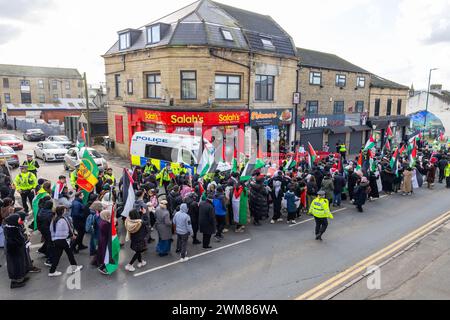 Bradford, Regno Unito. 24 FEBBRAIO 2024. La polizia protegge la presa di Salah su Leeds Road mentre la marcia per la Palestina del West Yorkshire passa cantando verso il negozio. Il negozio può ancora essere visto danneggiato a seguito di un violento confronto tra i proprietari dei negozi e i manifestanti pro palestina la notte prima a seguito di una disputa sul boicottaggio. Credito Milo Chandler/Alamy Live News Foto Stock