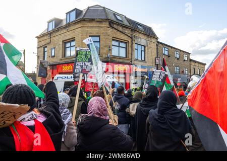 Bradford, Regno Unito. 24 FEBBRAIO 2024. La polizia protegge la presa di Salah su Leeds Road mentre la marcia per la Palestina del West Yorkshire passa cantando verso il negozio. Il negozio può ancora essere visto danneggiato a seguito di un violento confronto tra i proprietari dei negozi e i manifestanti pro palestina la notte prima a seguito di una disputa sul boicottaggio. Credito Milo Chandler/Alamy Live News Foto Stock