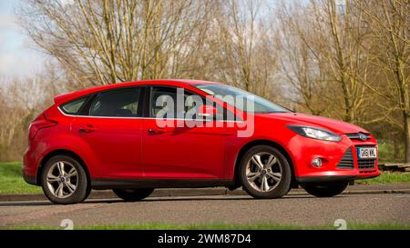 Milton Keynes, UK-23 febbraio 2024:2011 auto Ford Focus rossa che guida su una strada inglese Foto Stock