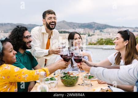 Gruppo di giovani amici che cenano sulla terrazza di casa Foto Stock