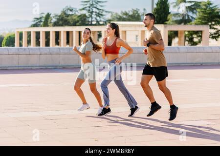 Tre giovani amici sportivi che corrono insieme in un parco urbano Foto Stock