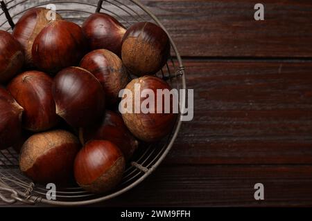 Castagne alimentari fresche e dolci in cesto di metallo su tavolo in legno, vista dall'alto. Spazio per il testo Foto Stock