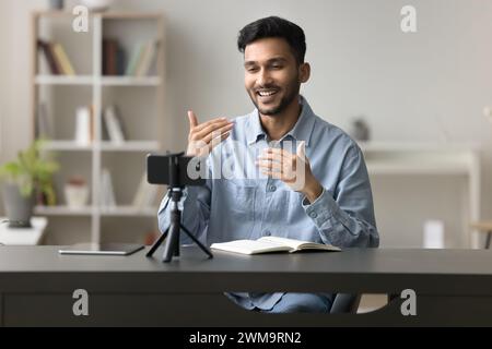 Il blogger maschile fa il discorso sulla fotocamera dello smartphone, sta su un treppiede Foto Stock