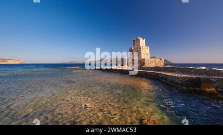 Un vecchio castello al tramonto che si affaccia sul mare calmo e sulla torre medievale ottagonale. Isolotto di Bourtzi, fortezza marina di Methoni, Peloponneso, Grecia Foto Stock