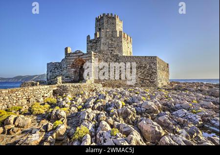 Rovine del castello illuminate dal sole su una scogliera rocciosa sopra il mare, torre medievale ottagonale. Isolotto di Bourtzi, fortezza marina di Methoni, Peloponneso, Grecia Foto Stock