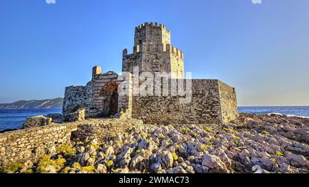 Rovine di un castello su una costa rocciosa con un cielo limpido, torre medievale ottagonale. Isolotto di Bourtzi, fortezza marina di Methoni, Peloponneso, Grecia Foto Stock