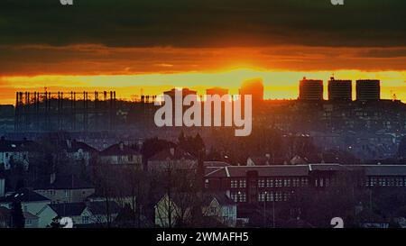Glasgow, Scozia, Regno Unito. 25 febbraio 2024. Meteo nel Regno Unito: Il sole rosso ardente sorge sull'estremità occidentale della città con il suo skyline di gotham. Credit Gerard Ferry/Alamy Live News Foto Stock