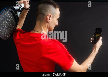 uomo con racchetta paddel e smartphone Foto Stock