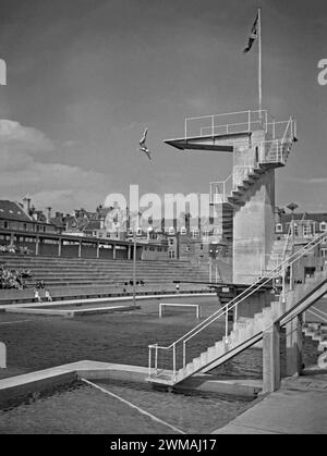 Una donna che si tuffa dalle tavole presso la piscina balneare Hastings St Leonards, Seaside Road, St Leonards-on-Sea, East Sussex, Inghilterra, Regno Unito c.1950. Il suggestivo lido è stato inaugurato nel 1933. La piscina è stata progettata e costruita da Sidney Little che era il Borough Engineer. L'enorme piscina era profonda 15 metri sotto la piattaforma di immersione in cemento. La piscina ospitava numerosi eventi di nuoto e immersioni, oltre a sfilate di moda e bellezza. A causa della popolarità delle vacanze all'estero, il numero dei bagni è diminuito e la piscina è chiusa nel 1959. Divenne un campo di vacanza (1960-86). Fu demolita nel 1993. Foto Stock