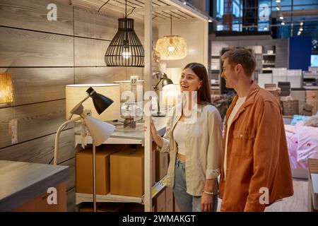 Giovani coppie di famiglie che scelgono il lampadario nel centro commerciale dell'edificio Foto Stock