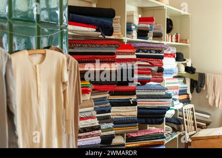 Tessuti in un negozio retrò. Negozio di abbigliamento e tessuti vintage. Uno scaffale pieno di prodotti colorati. Foto Stock