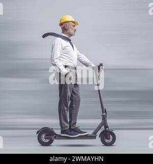 Ingegnere professionista che indossa un casco di sicurezza e guida uno scooter elettrico, ingegneria e tecnologia concetto Foto Stock