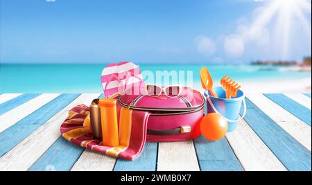 Borsa da viaggio, accessori colorati sulla spiaggia e mare sullo sfondo: Vacanze estive e concetto di viaggio Foto Stock