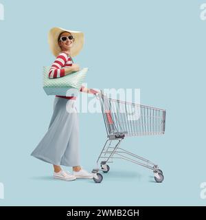 Giovane donna alla moda che spinge un carrello e sorride alla macchina fotografica Foto Stock
