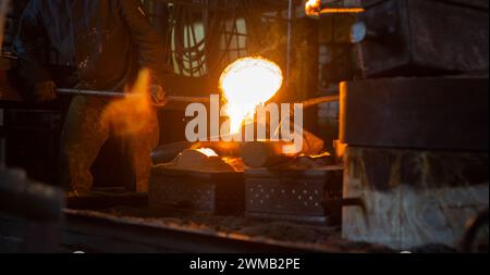 Versare il metallo fuso in uno stampo di sabbia nella fonderia dell'impianto metallurgico Foto Stock