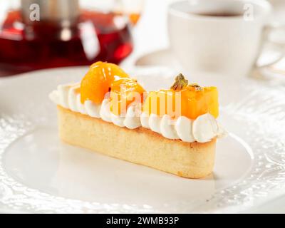 Crostata di cachi con panna montata. Deliziosa crostata soffice e cremosa con sosia dolce fresco su piatto bianco sullo sfondo del tavolo del ristorante. Idea di dessert con frutta di cachi Foto Stock