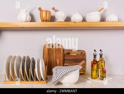 Cucina luminosa in una cucina moderna. Asciugamani, un set di stoviglie da cucina. Zucche decorative su un ripiano in legno aperto. Vista frontale Foto Stock