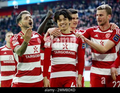 Duesseldorf, Germania. 25 febbraio 2024. Calcio: Bundesliga 2, fortuna Düsseldorf - Hansa Rostock, giorno 23, alla Merkur Spiel-Arena. Ao Tanaka (M) di Düsseldorf celebra il suo gol per 2:0 con i suoi compagni di squadra. Credito: Roland Weihrauch/dpa - NOTA IMPORTANTE: in conformità con i regolamenti della DFL German Football League e della DFB German Football Association, è vietato utilizzare o far utilizzare fotografie scattate nello stadio e/o della partita sotto forma di immagini sequenziali e/o serie di foto video./dpa/Alamy Live News Foto Stock