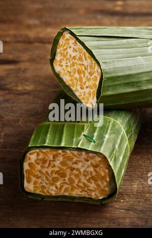 Tempeh crudo avvolto in foglie di banana. Il Tempeh è un tipico alimento indonesiano a base di soia fermentata e diversi altri ingredienti Foto Stock