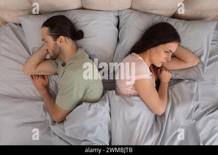 Una coppia a letto con vista l'una dall'altra, sconvolta Foto Stock