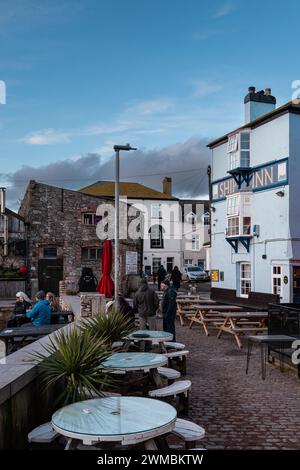 Lo Ship Inn a Teignmouth, Devon, Inghilterra, Regno Unito, con posti a sedere all'aperto e gente che beve in prima serata in inverno. Formato verticale Foto Stock