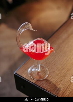 Cocktail cosmopolita in vetro di cigno, foto minimalista sul bordo del bancone del bar. Popolare cocktail alcolico cosmopolita a base di vodka, triple sec, succo di mirtillo, succo di lime. Menu a barre Foto Stock