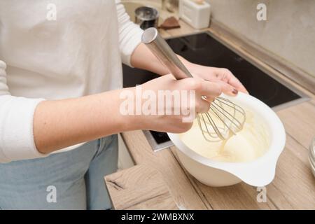 Primo piano delle mani di donna che sbattono l'impasto in una ciotola. Foto Stock