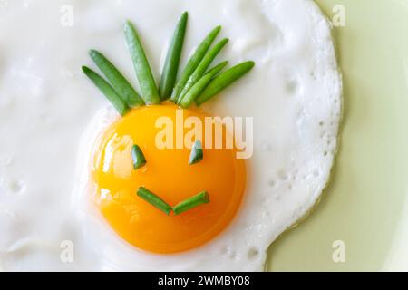 Divertente uovo fritto con sorriso sul piatto, concetto creativo per la colazione Foto Stock