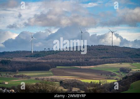 Windenergie im Einklang mit der Natur 25.02.24, Selters: Symbolfoto, Illustrationsbild, Symbolbild, Illustrationsfoto Windenergie im Einklang mit der Natur Dieses Bild zeigt drei beeindruckende Windräder, die aus einem dichten Wald herausragen. Im Vordergrund erstrecken sich weite Felder und Grüne Wiesen, die ein harmonisches Bild der nachhaltigen Energiegewinnung inmitten der Natur zeichnen. AM Horizont bilden sich malerische Quellwolken, Die dem Himmel eine dramatische Kulisse verleihen und die Verbindung zwischen Himmel und Erde symbolisieren. Selters Hessen Germania *** energia eolica in armo Foto Stock