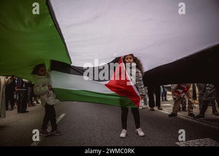 Barcellona, Spagna. 25 febbraio 2024. I bambini giocano sotto una gigantesca bandiera palestinese durante una manifestazione a sostegno del popolo palestinese. Crediti: Matthias Oesterle/Alamy Live News Foto Stock