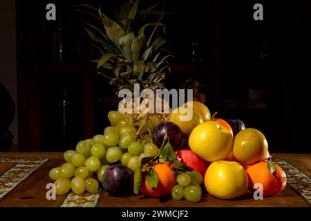 Primo piano di una pila di uva, mele, satsuma, prugne e ananas su una tavola Foto Stock